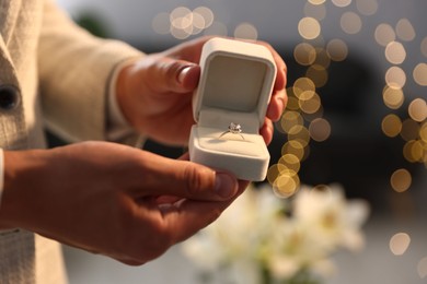 Photo of Making proposal. Man with engagement ring indoors, closeup. Bokeh effect