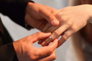 Photo of Making proposal. Man putting engagement ring on his girlfriend's finger indoors, closeup