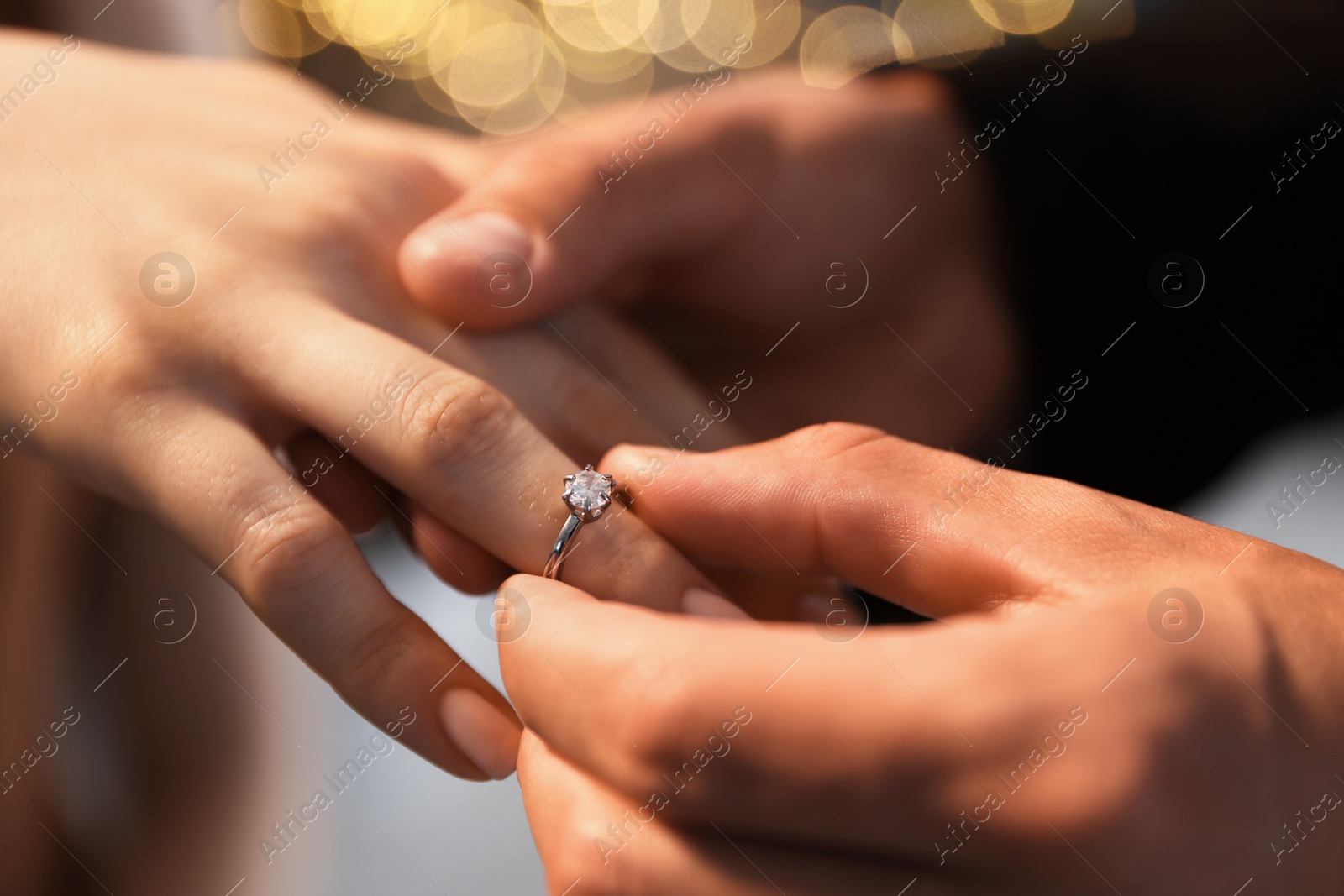 Making proposal. Man putting engagement ring on his girlfriend's finger indoors, closeup. Bokeh effect Photo of Making proposal. Man putting engagement ring on his girlfriend's finger indoors, closeup. Bokeh effect
