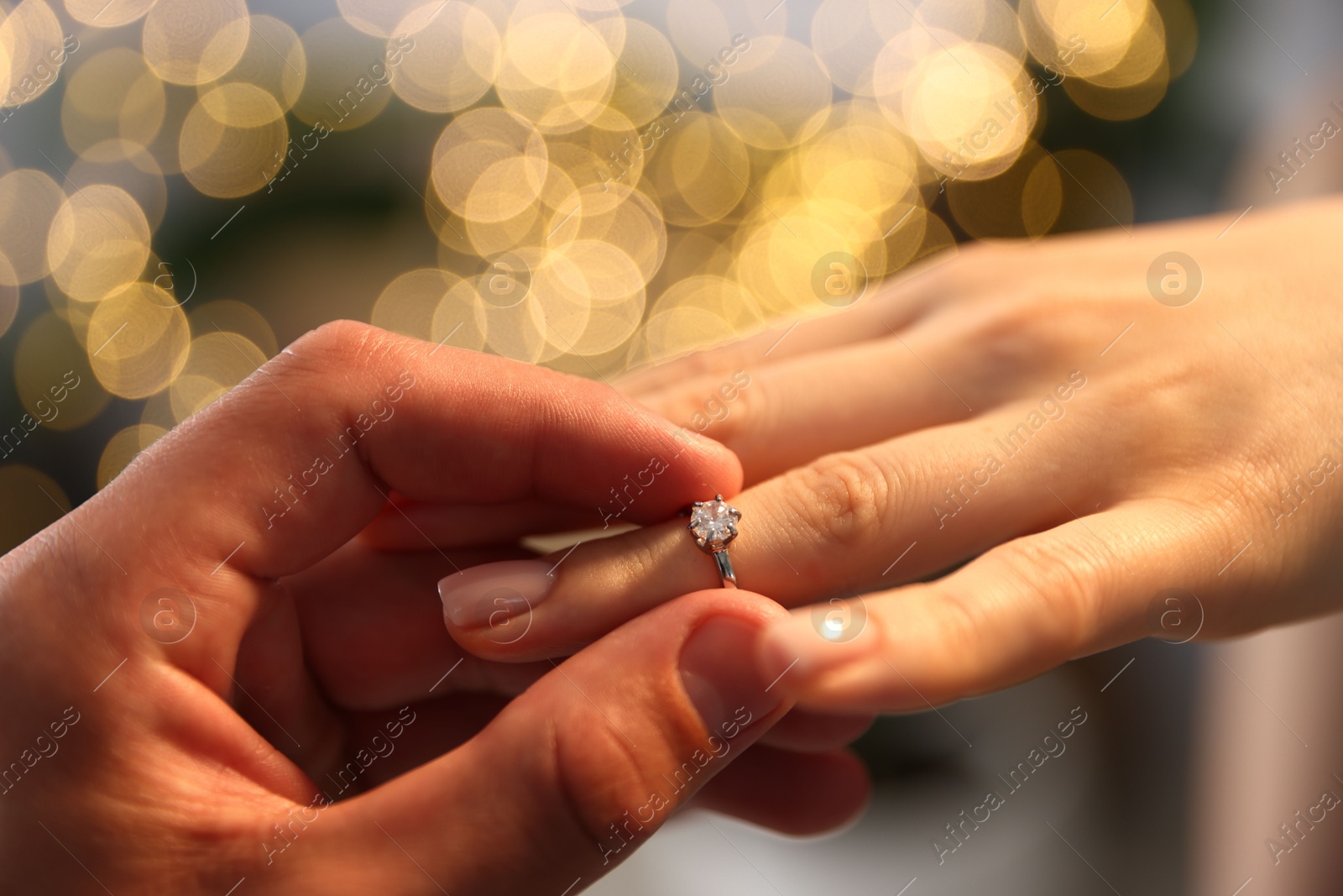Making proposal. Man putting engagement ring on his girlfriend's finger indoors, closeup. Bokeh effect Photo of Making proposal. Man putting engagement ring on his girlfriend's finger indoors, closeup. Bokeh effect