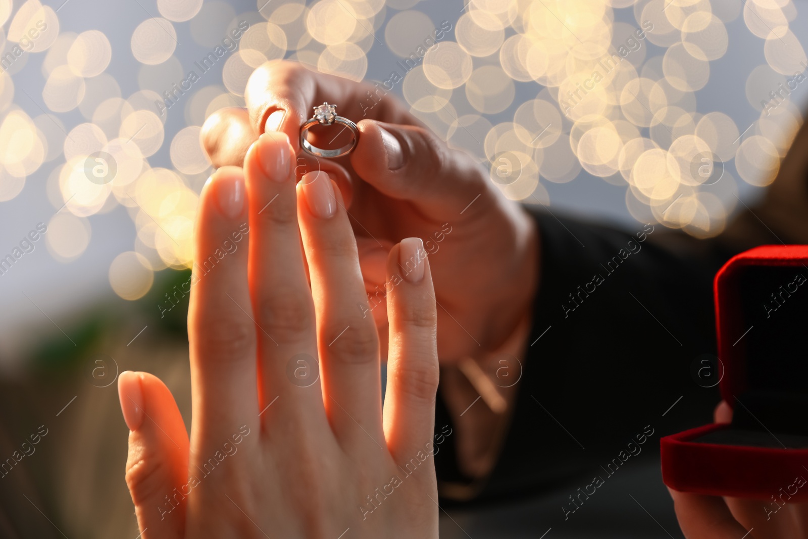 Making proposal. Man putting engagement ring on his girlfriend's finger indoors, closeup. Bokeh effect Photo of Making proposal. Man putting engagement ring on his girlfriend's finger indoors, closeup. Bokeh effect