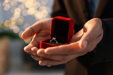 Photo of Making proposal. Man with engagement ring indoors, closeup. Bokeh effect