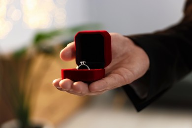 Photo of Making proposal. Man with engagement ring indoors, closeup. Bokeh effect