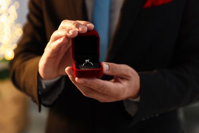 Photo of Making proposal. Man with engagement ring indoors, closeup. Bokeh effect