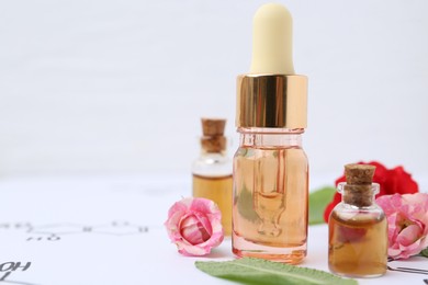 Photo of Bottles of cosmetic products, herbs and roses on paper with chemical formulas, closeup. Space for text