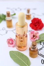 Photo of Bottles of cosmetic products, herbs and roses on paper with chemical formulas, closeup