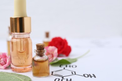 Photo of Bottles of cosmetic products, herbs and roses on paper with chemical formulas, closeup. Space for text