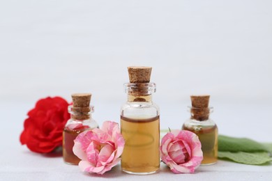 Photo of Bottles of cosmetic products, roses and sage on white table, closeup