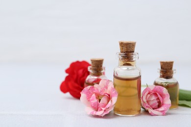 Photo of Bottles of cosmetic products and roses on white table, closeup. Space for text