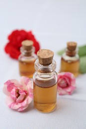 Photo of Bottles of cosmetic products and roses on white table, closeup