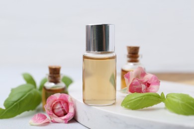 Photo of Bottles of cosmetic products, roses and basil on white table, closeup