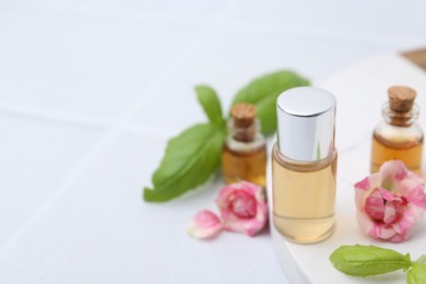 Photo of Bottles of cosmetic products, roses and basil on white table, closeup. Space for text