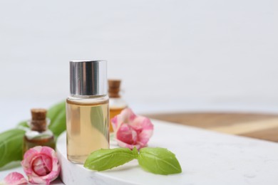 Photo of Bottles of cosmetic products, roses and basil on table, closeup. Space for text