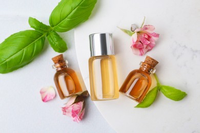 Photo of Bottles of cosmetic products, roses and basil on white table, flat lay