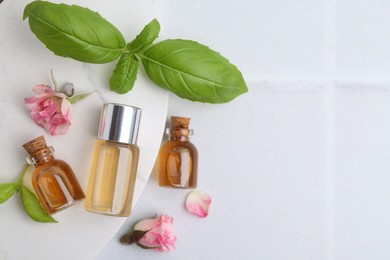 Photo of Bottles of cosmetic products, roses and basil on white table, flat lay. Space for text