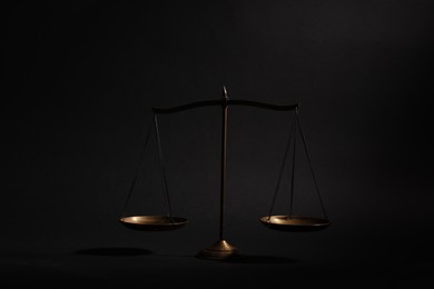 Photo of Golden scales of justice on black background