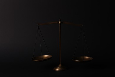 Photo of Golden scales of justice on black background