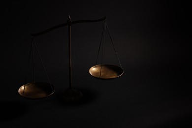 Photo of Golden scales of justice on black background