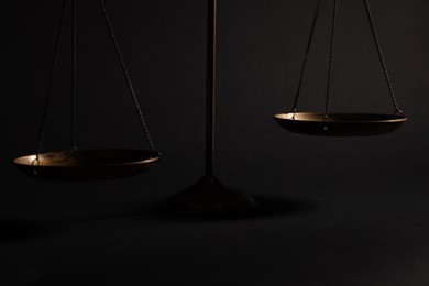 Photo of Golden scales of justice on black background, closeup