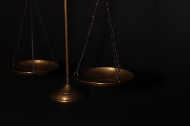 Photo of Golden scales of justice on black background, closeup