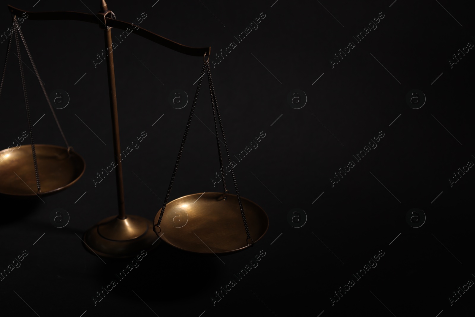 Photo of Golden scales of justice on black background, closeup. Space for text