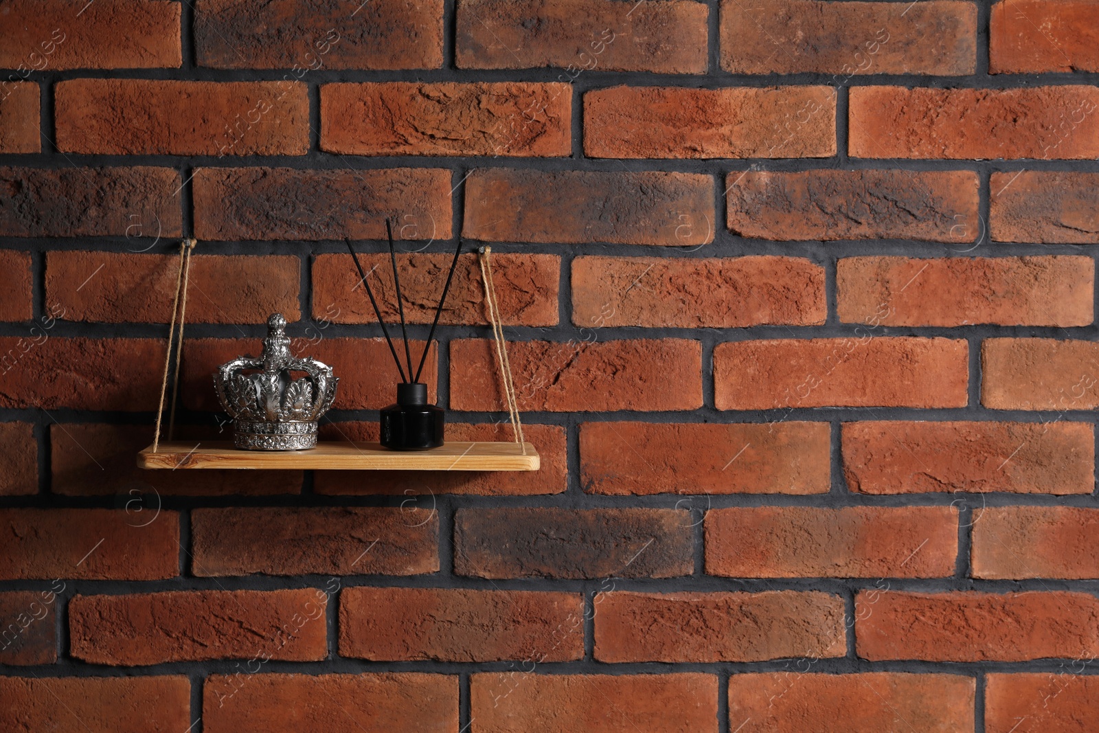 Photo of Wooden shelf with reed diffuser and home decor on brick wall, space for text
