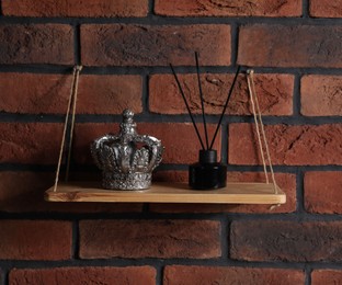Photo of Wooden shelf with reed diffuser and home decor on brick wall