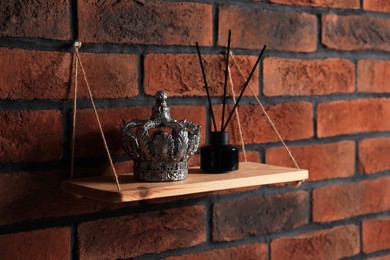 Photo of Wooden shelf with reed diffuser and home decor on brick wall