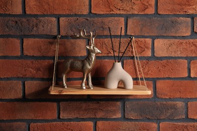 Photo of Wooden shelf with reed diffuser and home decor on brick wall