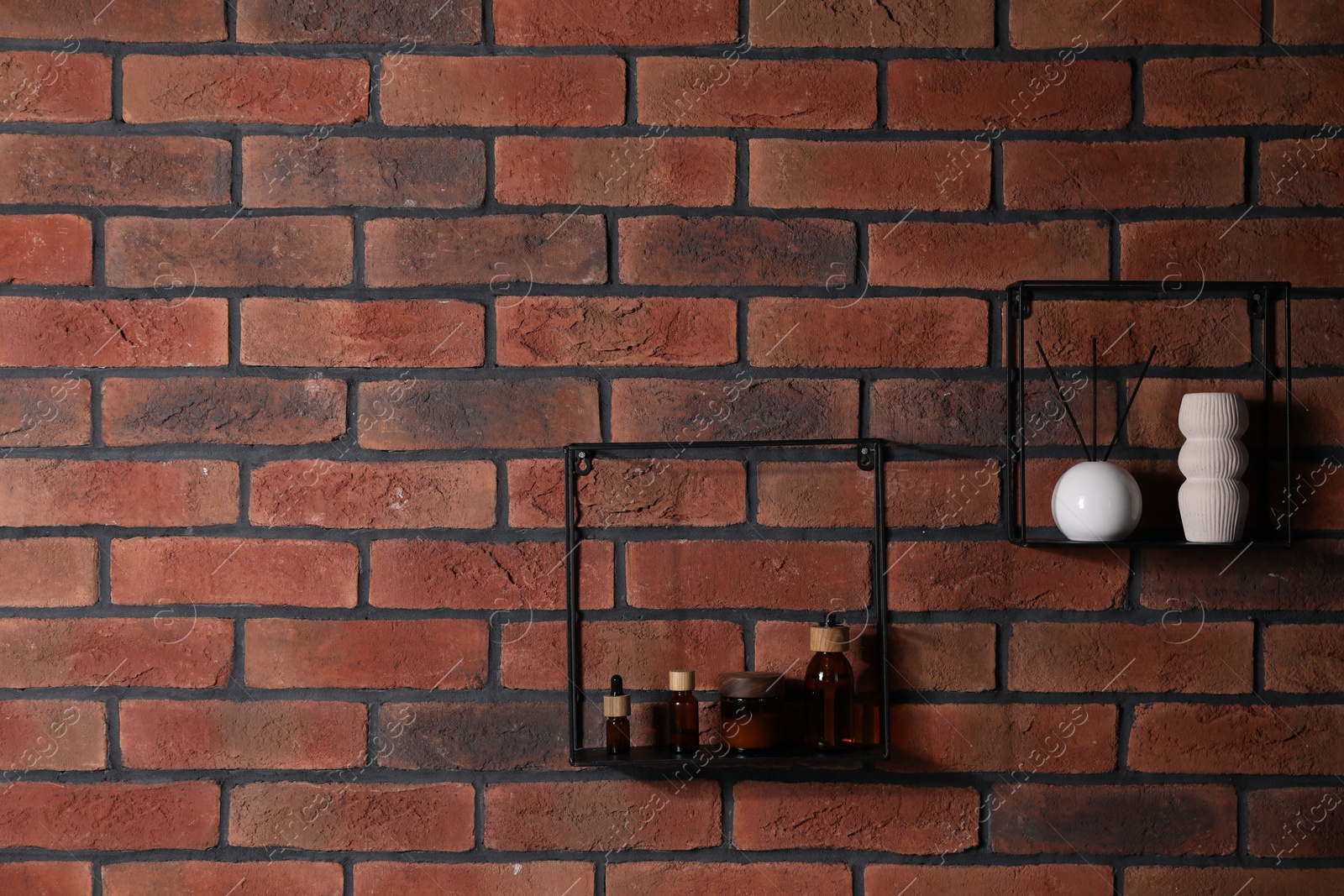 Photo of Square shaped shelves with cosmetic product and home decor on brick wall, space for text