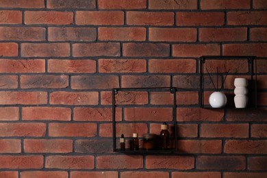 Photo of Square shaped shelves with cosmetic product and home decor on brick wall, space for text