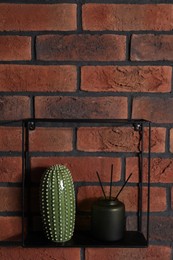 Photo of Square shaped shelf with home decor on brick wall, space for text