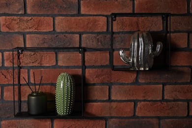 Photo of Square shaped shelves with home decor on brick wall