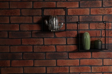 Photo of Square shaped shelves with home decor on brick wall, space for text