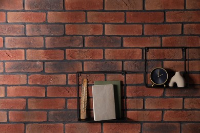 Photo of Square shaped shelves with books and home decor on brick wall, space for text