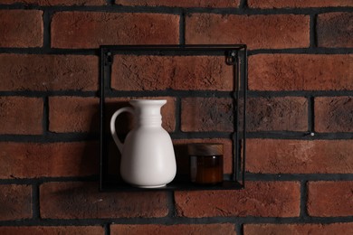 Photo of Square shaped shelf with vase and cosmetic product on brick wall