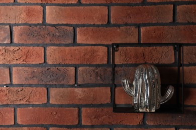 Photo of Square shaped shelf with cactus statue on brick wall, space for text