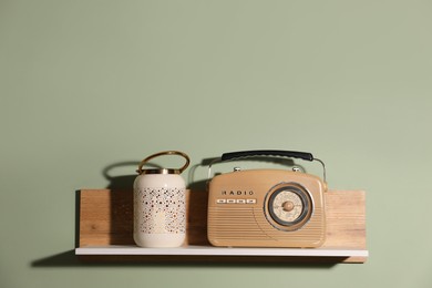 Photo of White wooden shelf with lamp and radio receiver on light green wall, space for text