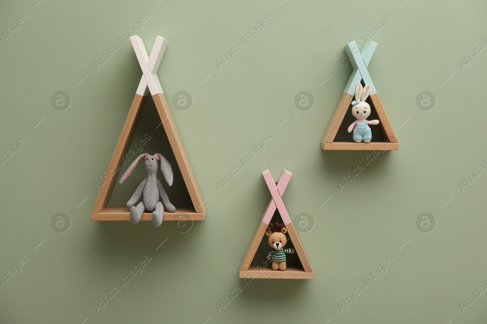 Photo of Triangle shaped shelves with toys on light green wall