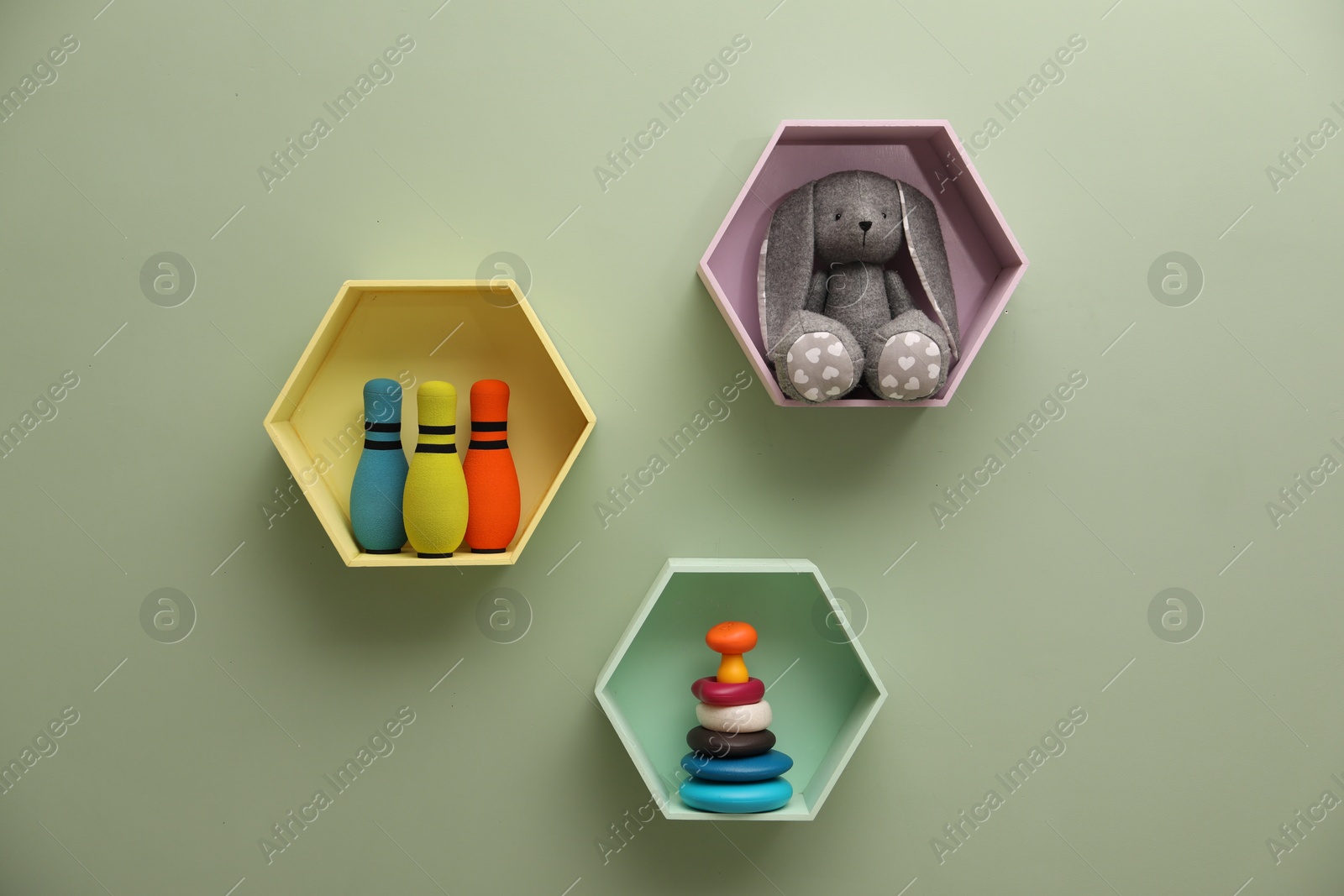 Photo of Honeycomb shaped shelves with toys on light green wall