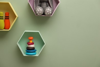 Photo of Honeycomb shaped shelves with toys on light green wall, space for text