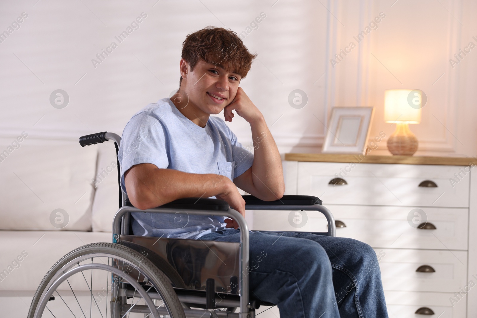 Photo of Smiling teenage boy in wheelchair at home