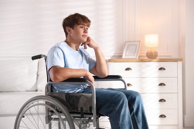Photo of Thoughtful teenage boy in wheelchair at home
