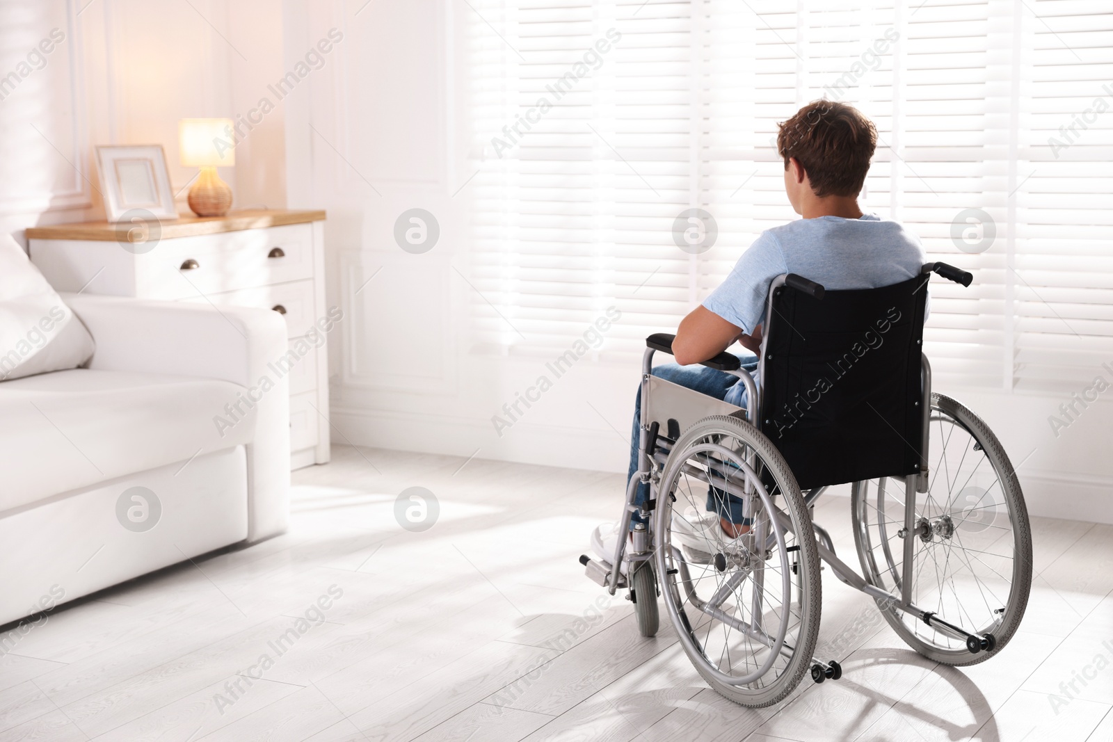Photo of Teenage boy in wheelchair in light room