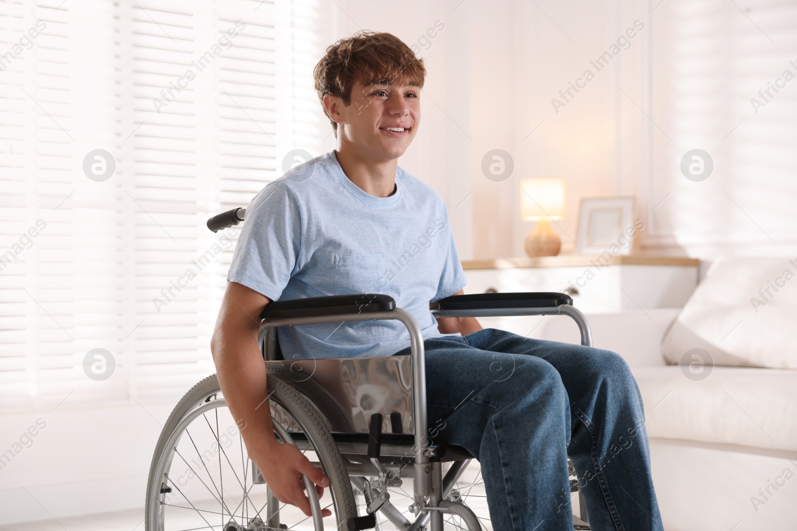 Photo of Smiling teenage boy in wheelchair at home