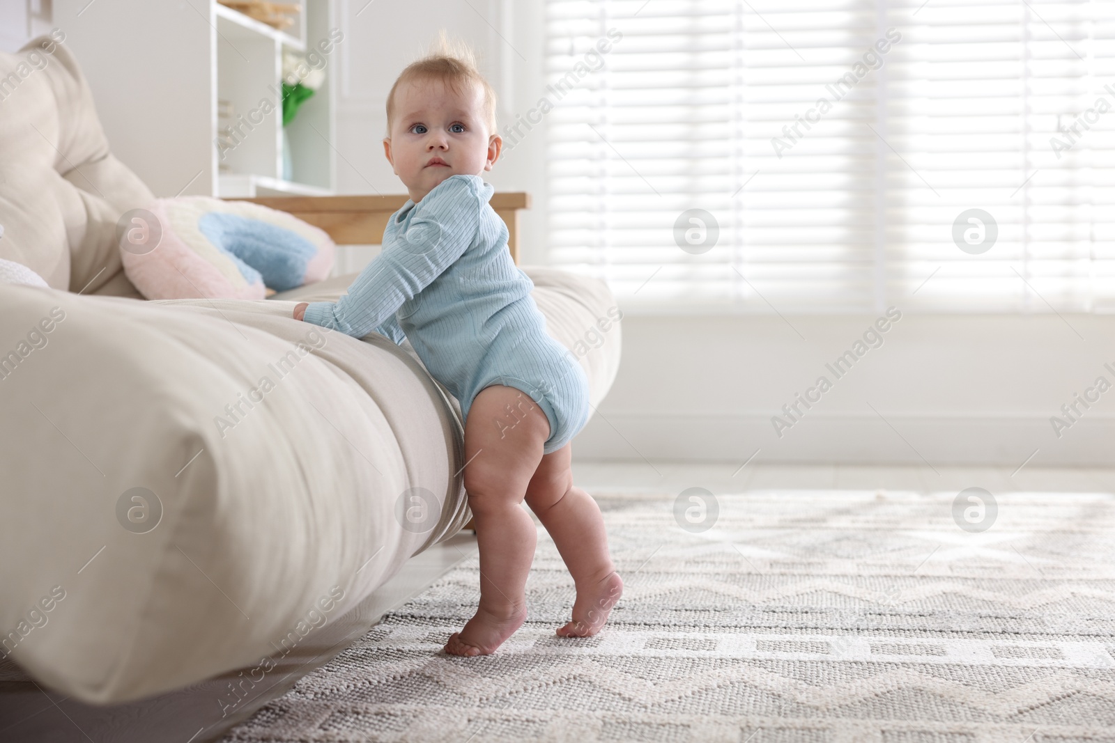 Cute little baby near sofa at home, space for text Photo of Cute little baby near sofa at home, space for text
