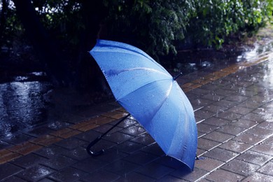Photo of Blue umbrella on wet asphalt under heavy rain