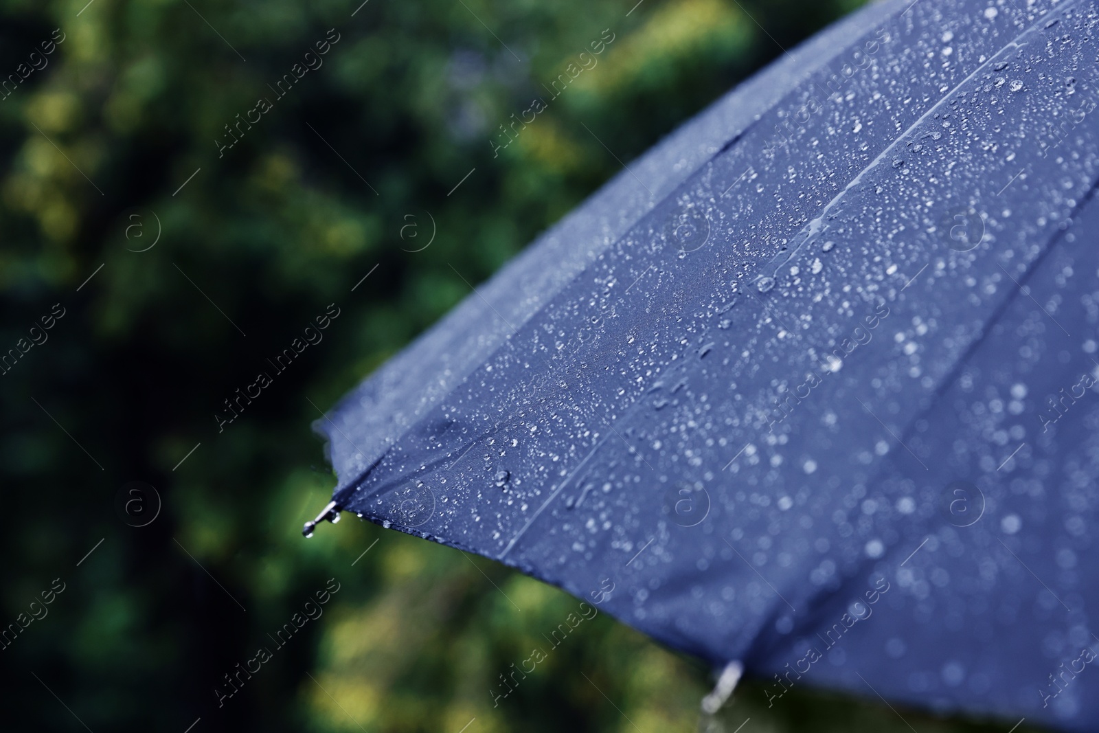 Photo of Blue umbrella under heavy rain outdoors, closeup. Space for text