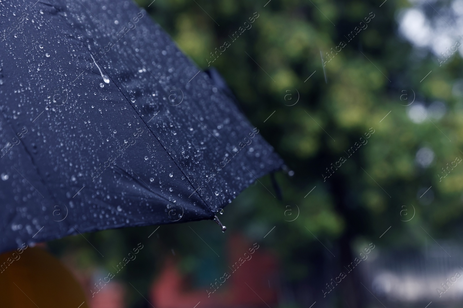 Photo of Blue umbrella under heavy rain outdoors, closeup. Space for text