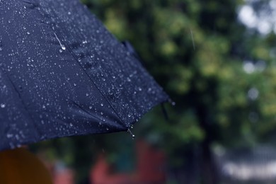 Photo of Blue umbrella under heavy rain outdoors, closeup. Space for text
